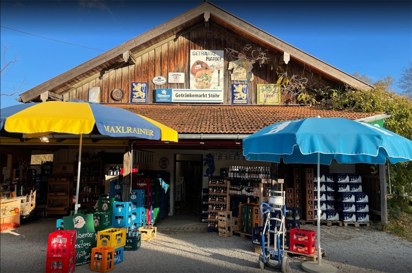 Der Getränkemarkt im Torfwerk in Bad Feilnbach von außen, mit Getränkekisten und Sonnenschirmen vor dem Eingang